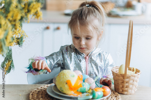 Cute adorale baby girl plays with colorful easter eggs at home