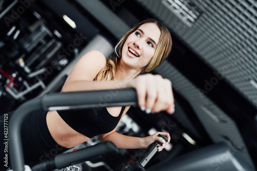 Portrait of a smiling attractive girl on a cardio machine during a workout