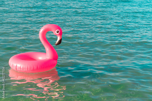 Summer sale. Pink inflatable flamingo in blue ocean water for sea summer beach background. Minimal summer concept. © Maksym