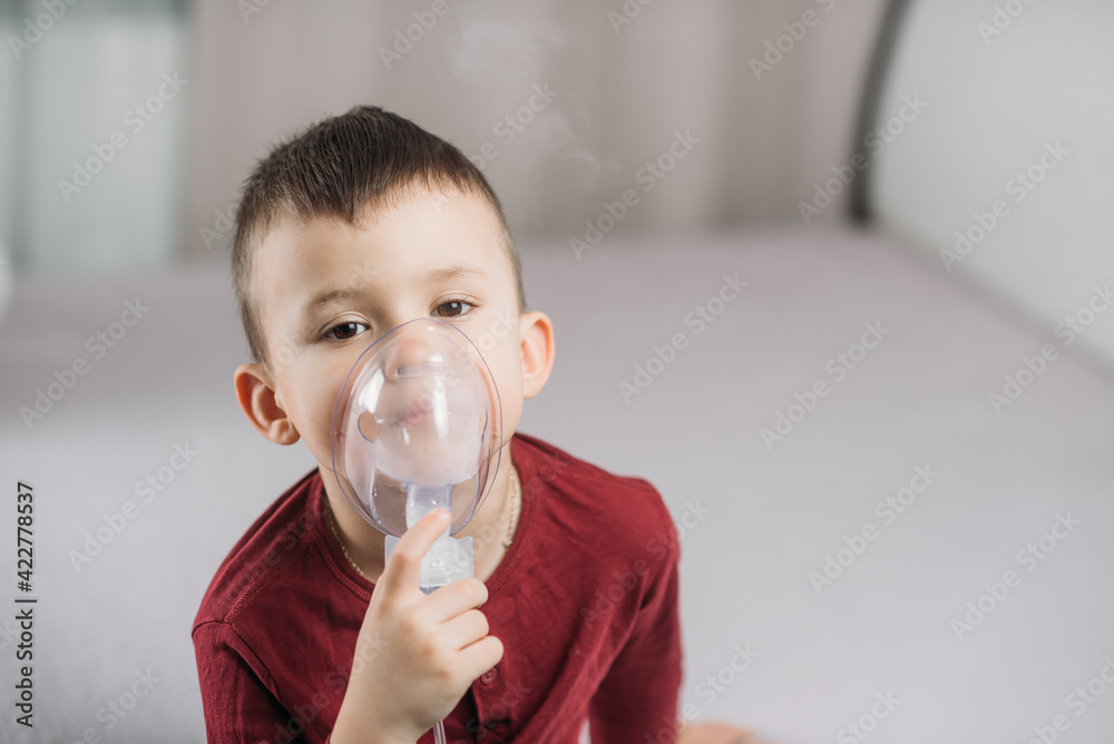 the child sitting on the bed in the bedroom makes an inhalation on their own