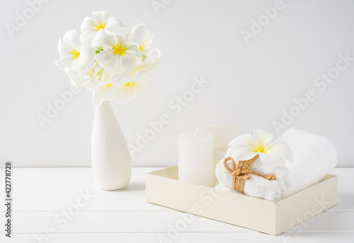 Fototapeta Naklejka Na Ścianę i Meble -  Spa composition beautiful plumeria flowers,white candles  and towels on wooden tray onver white wood table room interior background