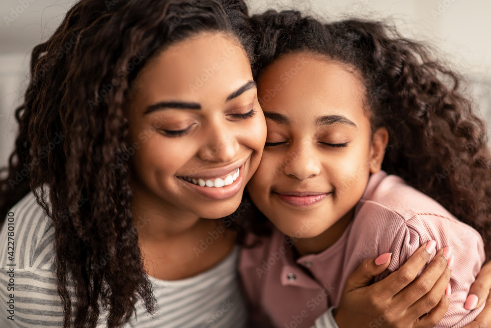 Closeup portrait of black mother and daughter hugging Closeup portrait of black mother and daughter hugging