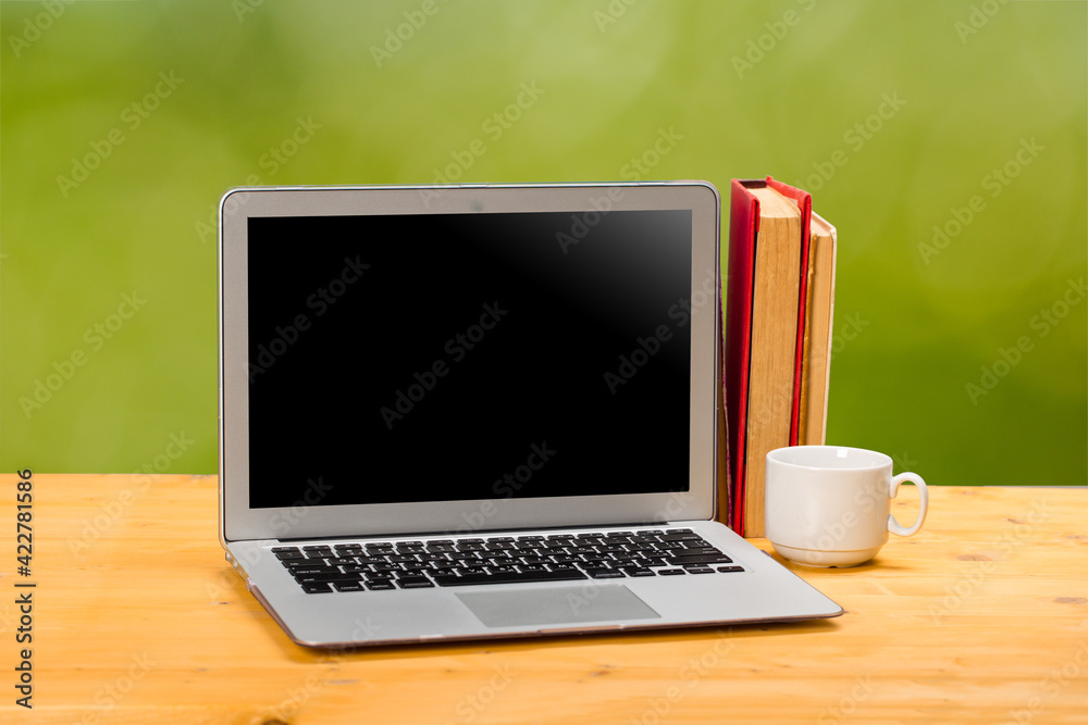 Laptop with blank screen, cup of coffee and books or notebooks on a wooden table. mockup for your text Laptop with blank screen, cup of coffee and books or notebooks on a wooden table. mockup for your text