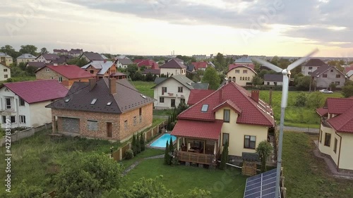 Wallpaper Mural Aerial view of suburban homes and private house with green grass covered yard, solar panels on roof, swimming pool with blue water and wind turbine generator. Torontodigital.ca