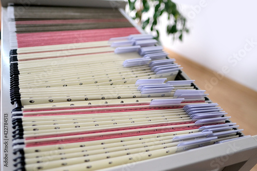 archival metal cabinet with thin files with information in the room  a home archive with folders  selective focus  a concept of a detective dossier  a file cabinet