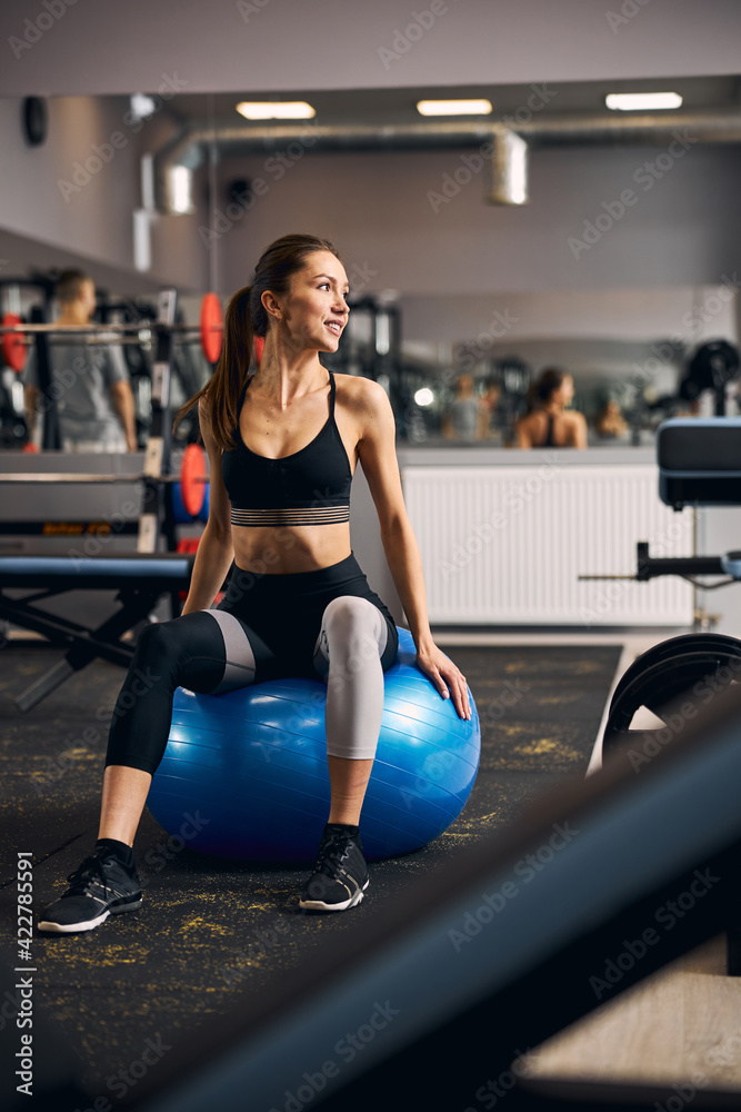 Positive delighted female sitting on fitness ball Positive delighted female sitting on fitness ball