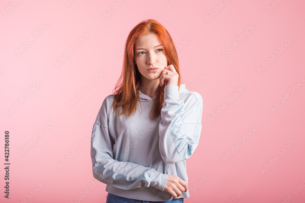 Portrait of a redhead pensive girl in the studio on a pink background Portrait of a redhead pensive girl in the studio on a pink background