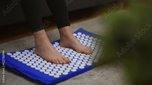 Woman is using acupuncture applicator mat for her legs. photo