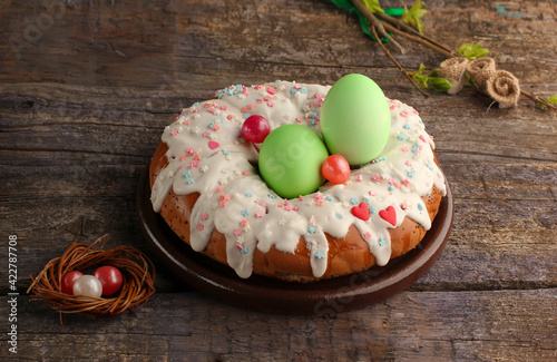 close up of  еaster cake with white icing green eggs  small nest  branch on an old wooden background
with copy  space
