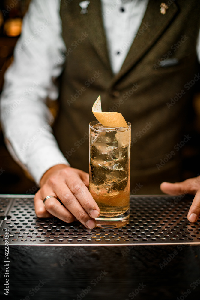 view on glass with cold drink decorated with citrus peel on bar counter