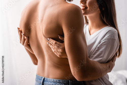 Cropped view of smiling woman touching muscular back of boyfriend