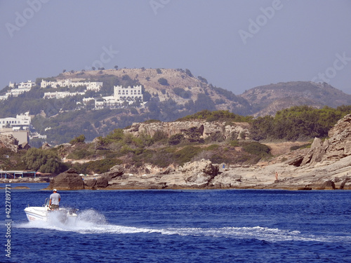 Motorboat at sea and rocky land with buildings
