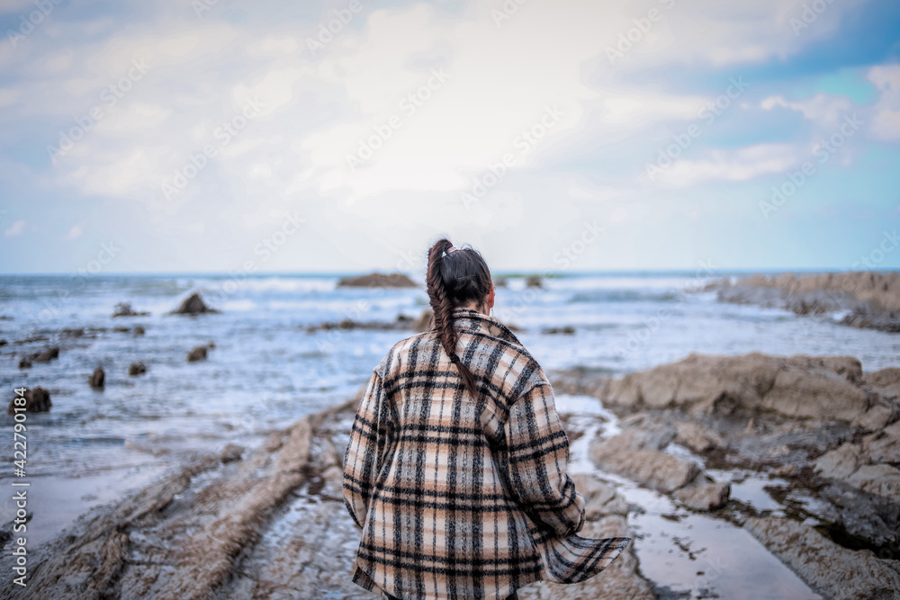 Brunette girl with braid walking on a rocky beach