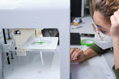 Researcher adjusting a 3D bioprinter to 3D print cells onto an electrode. Biomaterials, tissue engineering concepts. photo