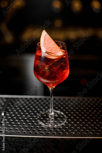 beautiful wine glass with bright cold iced drink decorated with citrus slice on bar