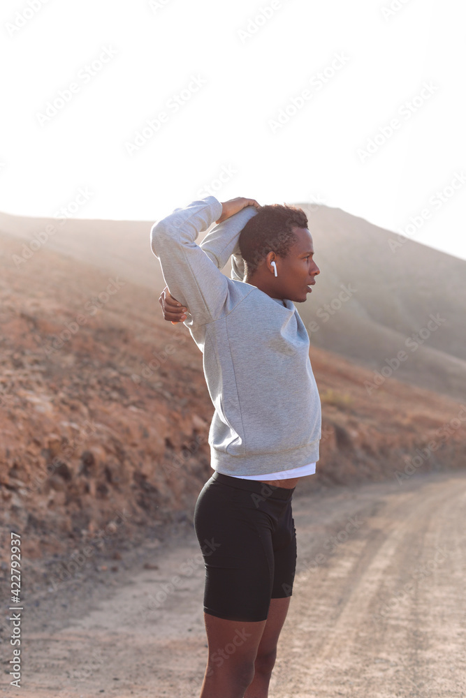 Man doing sport in a desert volcanic valley - Athlete listening to music while training outdoor