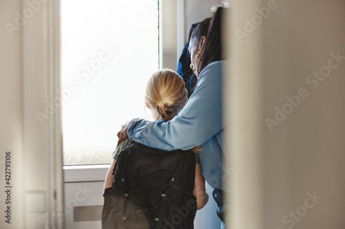 Mom helping her daughter put on a backpack for school