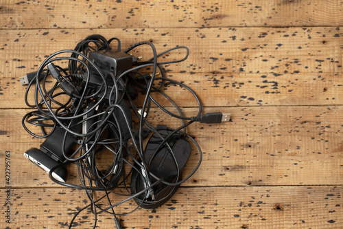 Close up view of tangled black wires and cables on the wooden background.