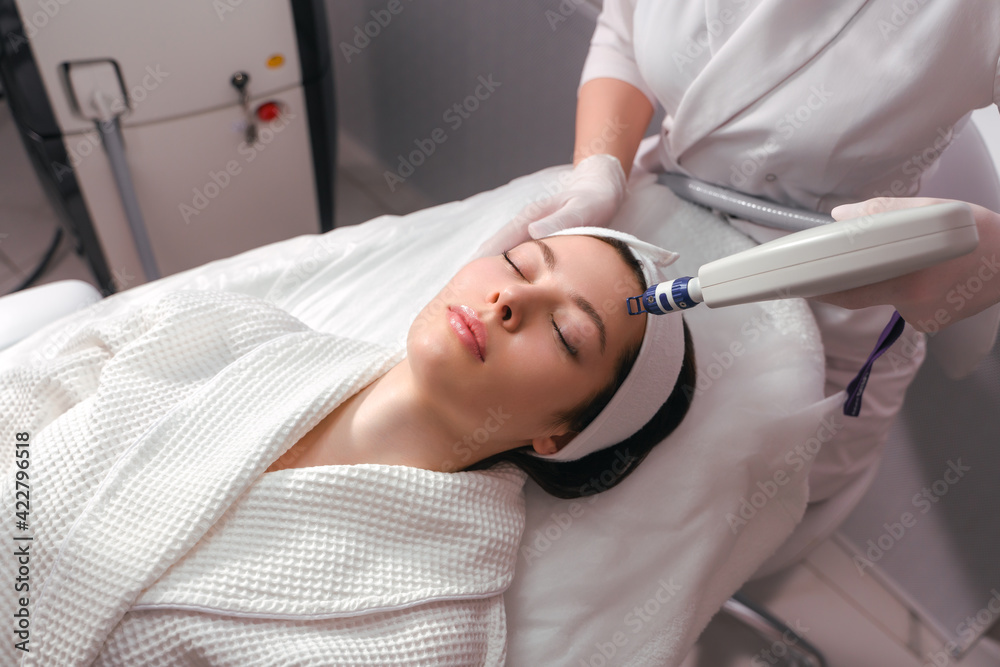 A woman receives laser treatment of the face in a cosmetology clinic, a concept of skin rejuvenation is being developed. laser peeling