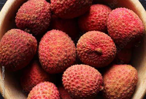 Photograph of many litchies also called lychees  in a wooden bowl for food background