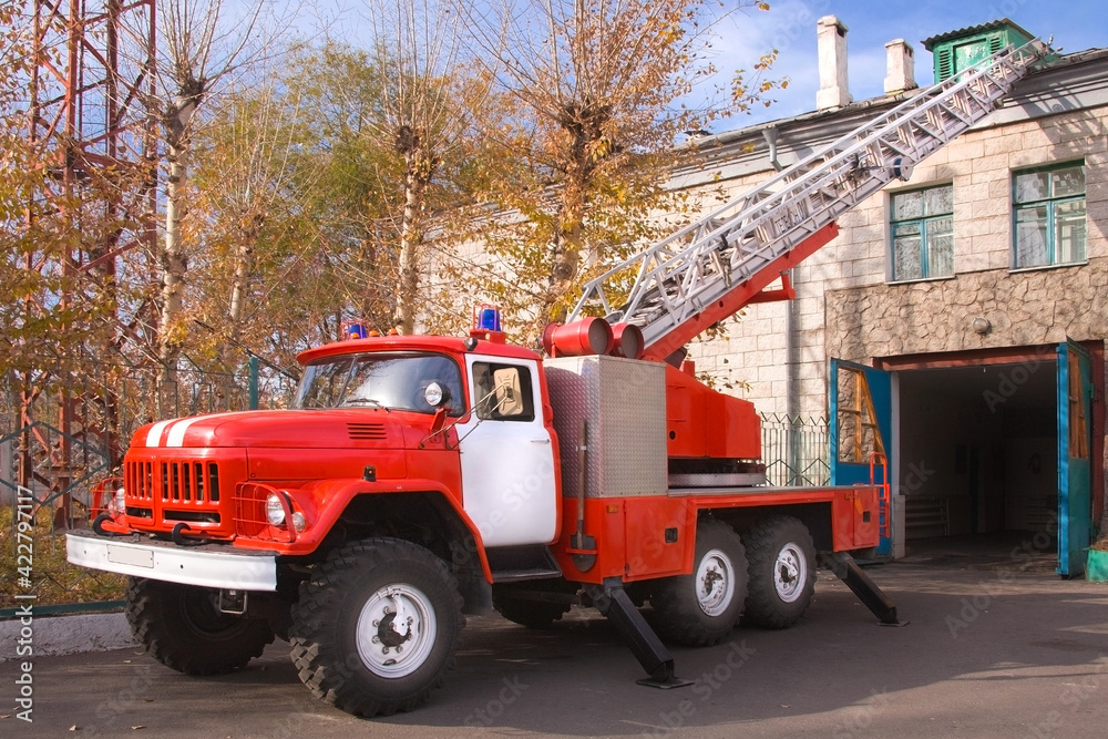 A large soviet red fire truck is preparing to leave.