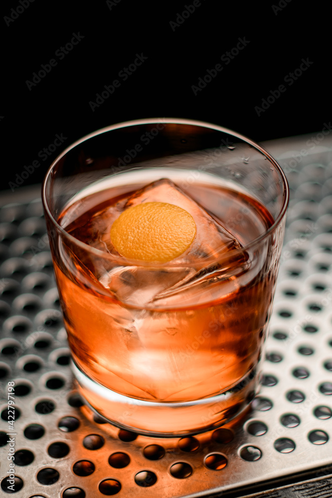 close-up of glass with drink and ice cube on steel surface of bar counter close-up of glass with drink and ice cube on steel surface of bar counter