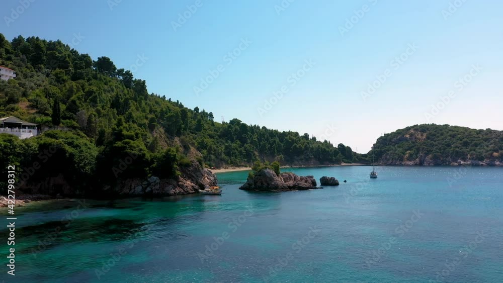 Aerial drone views over a rocky coastline, crystal clear Aegean sea waters, touristic beaches and lots of greenery in Skopelos island, Greece. A typical view of many similar Greek islands.