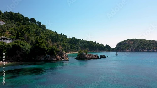 Aerial drone views over a rocky coastline, crystal clear Aegean sea waters, touristic beaches and lots of greenery in Skopelos island, Greece. A typical view of many similar Greek islands.