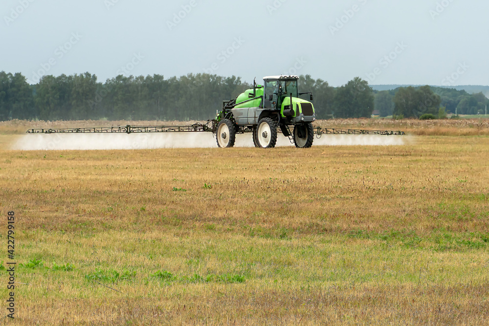 self-propelled sprayer works in the field on a warm sunny day. Weed control with pesticides and chemicals. The tractor uses a sprayer to spray liquid fertilizers in the field. self-propelled sprayer works in the field on a warm sunny day. Weed control with pesticides and chemicals. The tractor uses a sprayer to spray liquid fertilizers in the field.
