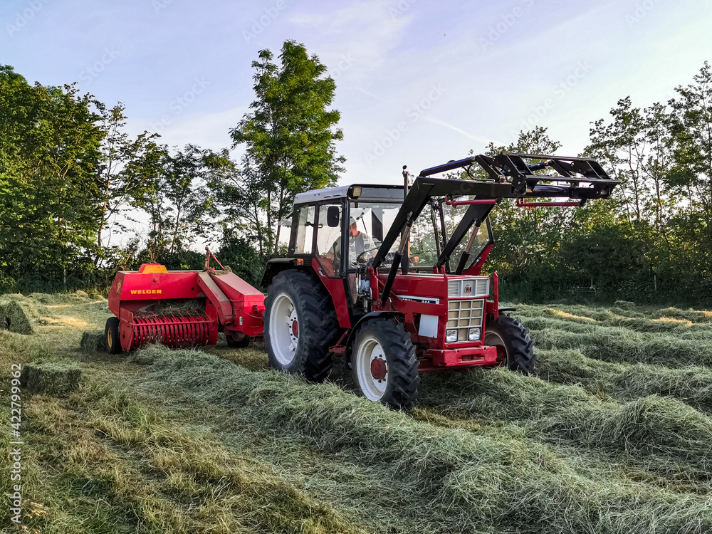 tractor in field pressing packs of hay in northern Germany, Schleswig Holstein. tractor in field pressing packs of hay in northern Germany, Schleswig Holstein.