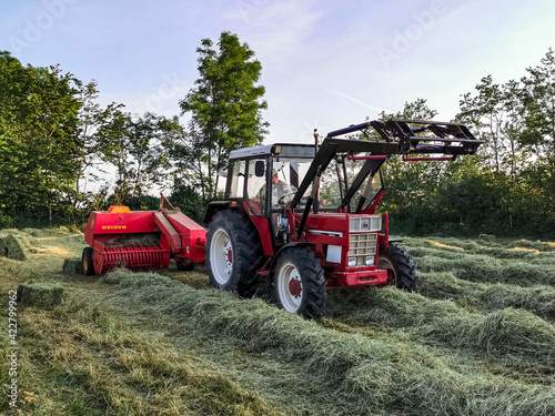 tractor in field pressing packs of hay in northern Germany  Schleswig Holstein.