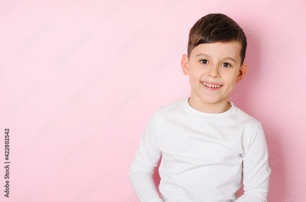 Happy smiling boy 6 years old in white t-shirt on pink studio background. Portrait of a laughing boy on a pink background Happy smiling boy 6 years old in white t-shirt on pink studio background. Portrait of a laughing boy on a pink background