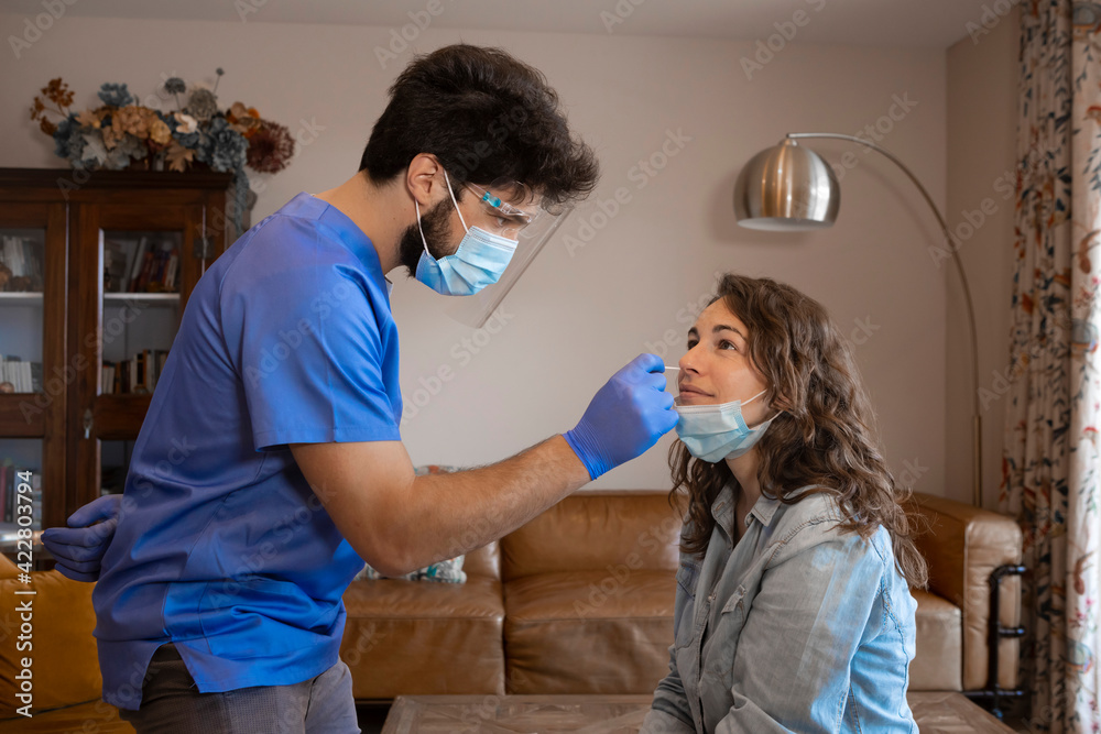 Medical staff member with mask and protective equipment performs fast antigen testing for SARS-CoV-2 (COVID-19, Coronavirus) nasal swabs test tubes at home medical visit. Medical staff member with mask and protective equipment performs fast antigen testing for SARS-CoV-2 (COVID-19, Coronavirus) nasal swabs test tubes at home medical visit.