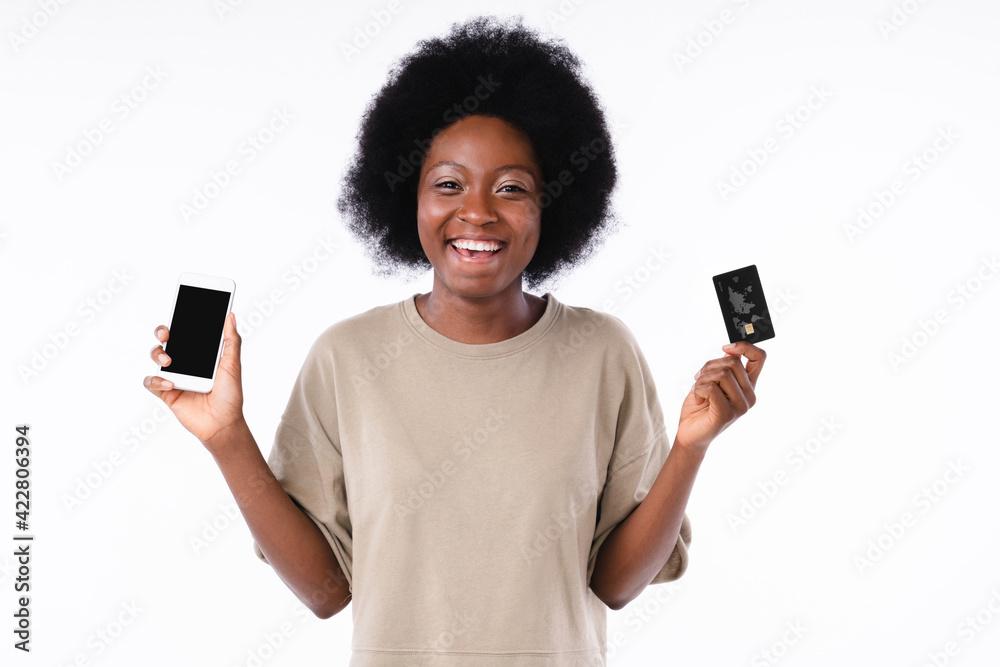 Cheerful african girl holding smart phone and credit card isolated in white Cheerful african girl holding smart phone and credit card isolated in white