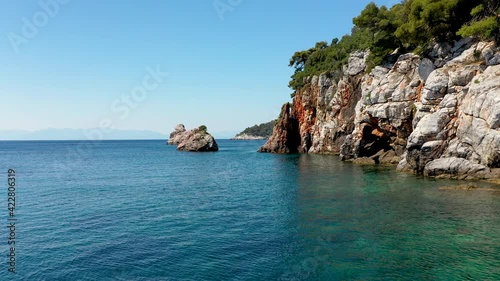 Aerial drone views over a rocky coastline, crystal clear Aegean sea waters, touristic beaches and lots of greenery in Skopelos island, Greece. A typical view of many similar Greek islands.