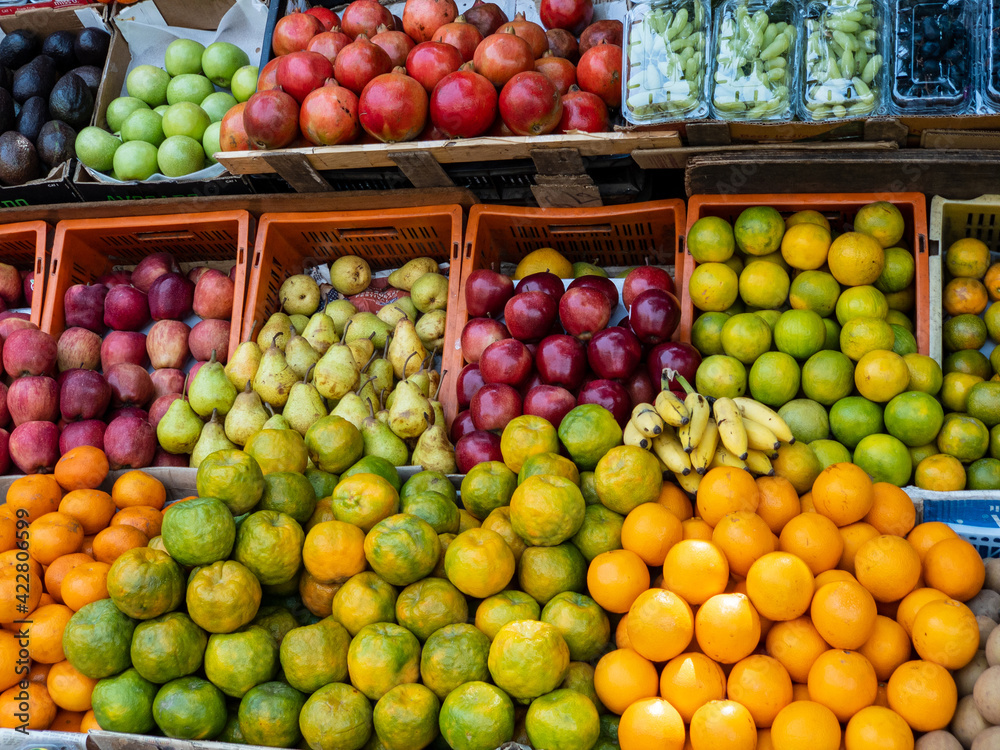 Multi colored fruits piled in crates, on display in the market, apples, oranges, pears, avacado, pomegranate, grapes