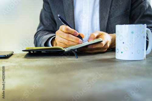 Detalle hombre escribiendo con taza en oficina mesa de trabajo