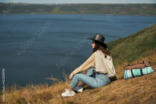 Female tourist sitting on hill and looking at Dniester river