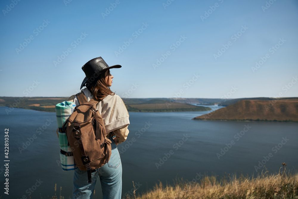 Active female hiker with backpack standing on top of hill Active female hiker with backpack standing on top of hill