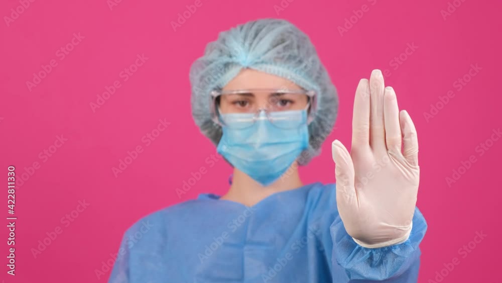 Doctor in a blue medical coat, safety glasses and medical cap making stop gesture. Doctor in a blue medical coat, safety glasses and medical cap making stop gesture.