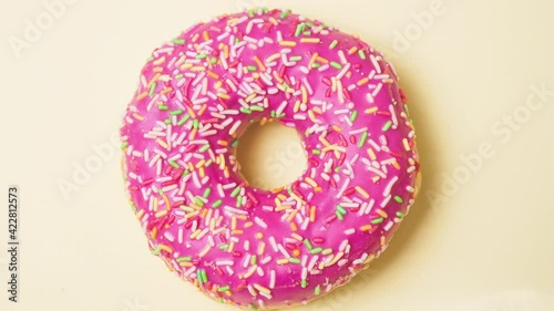 Bright donut in a pink glaze with a multi-colored rainbow sprinkle on a pink background. Sweets and desserts. Minimalistic background with clean place for the inscription. Copy space. Soft focus.