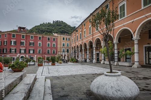 Cityscape. Carrara city center: Piazza Alberica with the commemorative monument in the center and the Ducal Palace , and small open doors cafes, shops in Tuscany, Italy photo