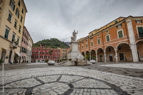 Cityscape. Carrara city center: Piazza Alberica with the commemorative monument in the center and the Ducal Palace , and small open doors cafes, shops in Tuscany, Italy photo