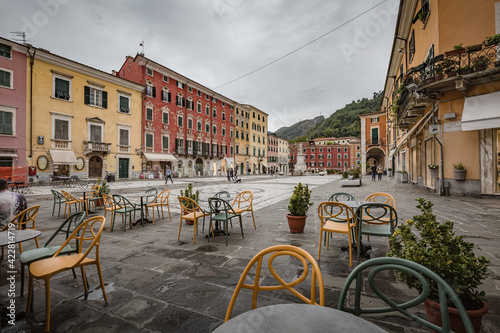 Cityscape. Carrara city center: Piazza Alberica with the commemorative monument in the center and the Ducal Palace , and small open doors cafes, shops in Tuscany, Italy photo