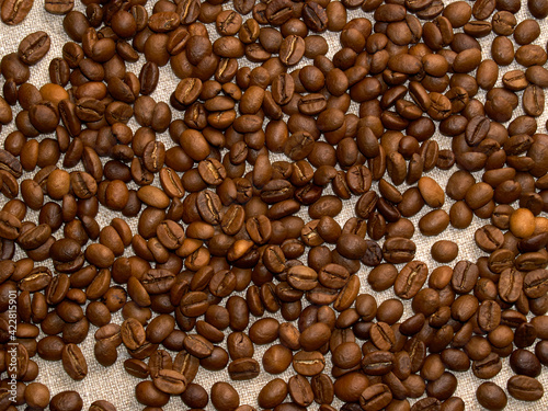Roasted coffee beans scattered on a burlap napkin.coffee background
