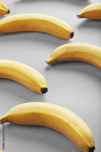 Geometric pattern of yellow bananas on a gray background in the Fashionable colors of 2021.