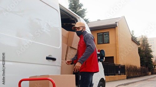 Young delivery man putting parcel into the van. Delivery during covid outbreak. High quality photo