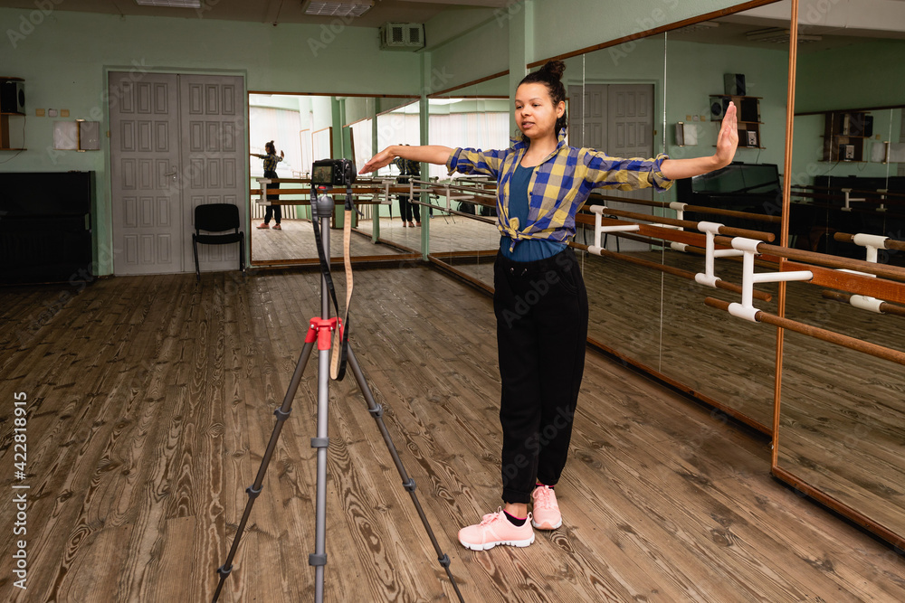 Young woman vlogger records dance on camera on tripod in choreographic hall. Young woman vlogger records dance on camera on tripod in choreographic hall.
