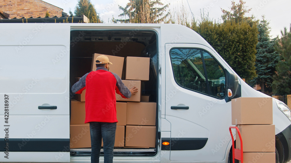 Delivery man putting parcel into the van. Delivery during covid outbreak. High quality photo Delivery man putting parcel into the van. Delivery during covid outbreak. High quality photo