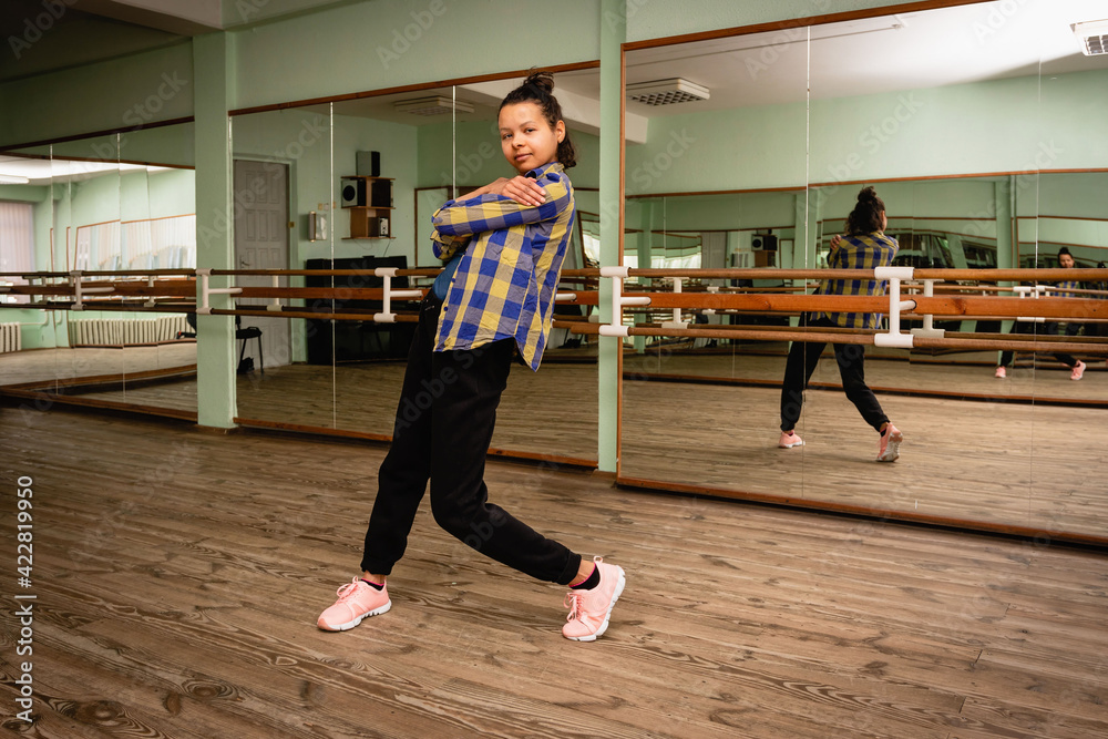 Young woman performs a beautiful dance movement in the choreography hall. Modern dance. Self-training alone